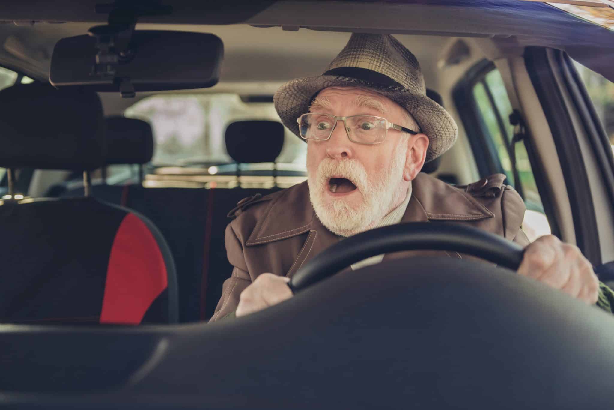 Photo of retired old man surprised face open mouth drive wear brown jacket headwear eyewear inside car